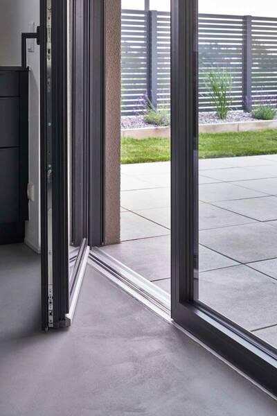Die zweiflügeligen Balkontüren mit Nullschwelle bieten barrierefreien Zugang und verlängern den Wohnraum mit ihren großzügigen Glasflächen nahtlos nach draußen