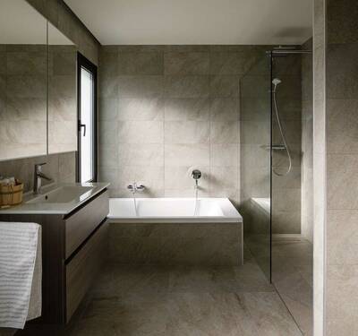 Das Badezimmer verströmt kontemplative Ruhe durch kluge Raumaufteilung, den gekonnten Einsatz von Licht und die harmonische Anmutung der Wand- und Bodenfliesen, die exakt positioniert und auch im Detail sauber verarbeitet sind