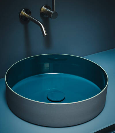 Ein Zusammenspiel von Form und Farbe: Der Waschtisch TRI-COLOR aus Vitreon Stahl, die Kartell LAUFEN Armatur und das ARUN Möbel bilden eine harmonische Einheit