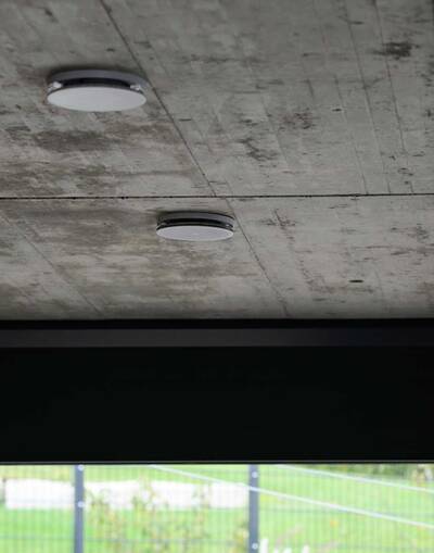 Haustechnik kann auch stylisch sein: So korrespondieren die weißen Tellerventile aus der Modellserie „Zehnder ComfoValve Luna“ hervorragend mit der Sichtbetondecke im Wohnzimmer des Anwesens Schaffer