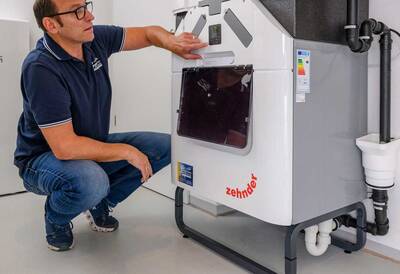 Im Keller ist das zentrale Komfort-Lüftungsgerät Zehnder ComfoAir Q verbaut und versorgt die Räume der modernen Immobilie mit frischer Luft. Im Bild überprüft Fachhandwerker Benedikt Kratzer die individuell programmierten Systemeinstellungen des Komfort-Lüftungssystems